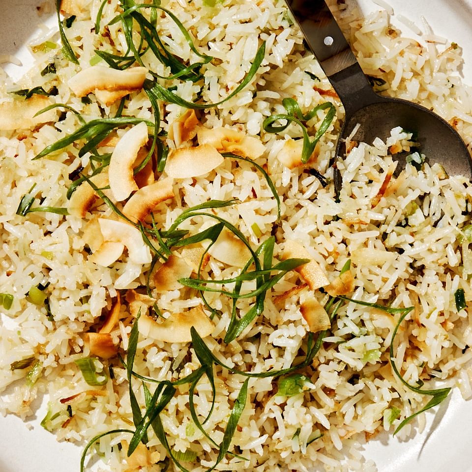 a bowl of homemade coconut fried rice made with coconut rice, green onions, ginger, coconut oil and sweetened coconut flakes