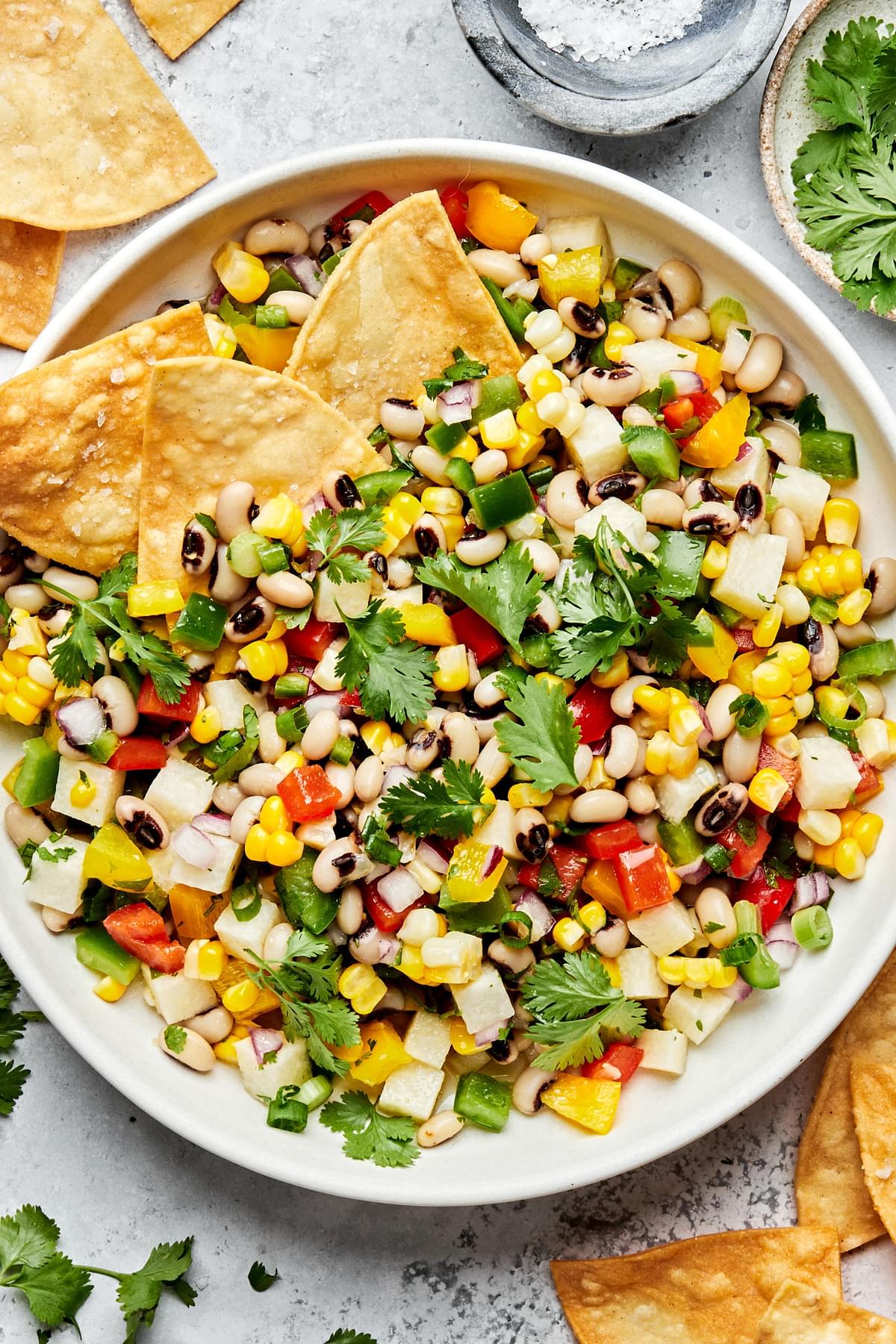 homemade cowboy caviar in a serving bowl with tortilla chips made with  black eyed peas, bell pepper, corn, jicama & cilantro
