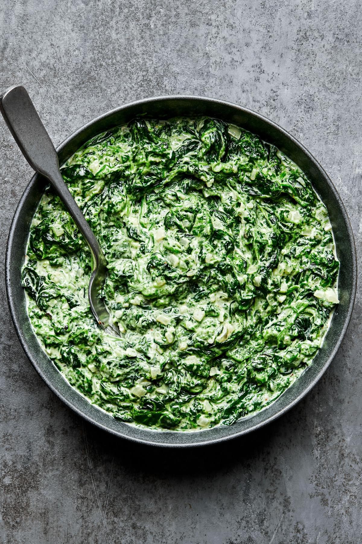 creamed spinach in a serving bowl made with butter, shallot, garlic, cream, dijon, spices and parmesan cheese