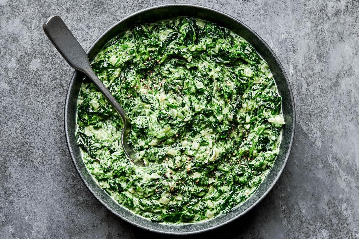 creamed spinach in a serving bowl made with butter, shallot, garlic, cream, dijon, spices and parmesan cheese