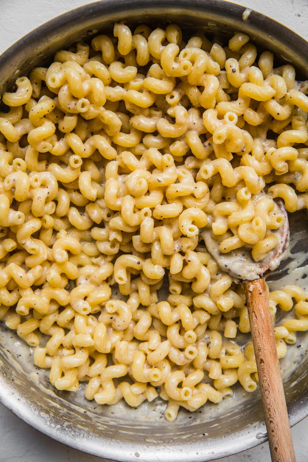 homemade Creamy Cavatappi Cacio e Pepe made with Romano and parmigiana cheeses in a pot being stirred with a spoon
