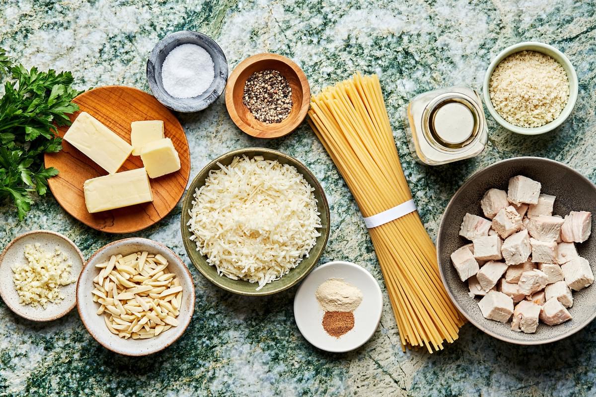 salt, noodles, butter, almonds, panko, garlic, spices, cream, parmesan, turkey & parsley in bowls for creamy turkey pasta