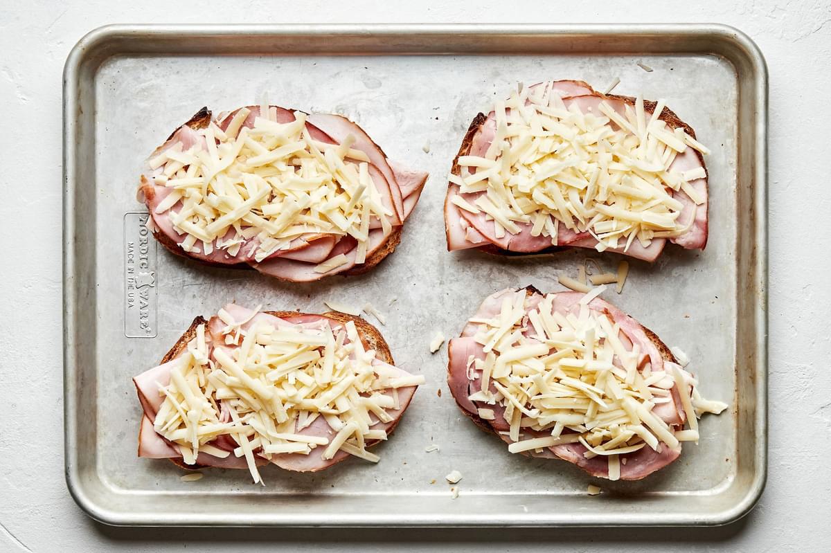 4 slices of buttered bread topped with ham and Gruyère cheese ready to be baked and make croque monsieur