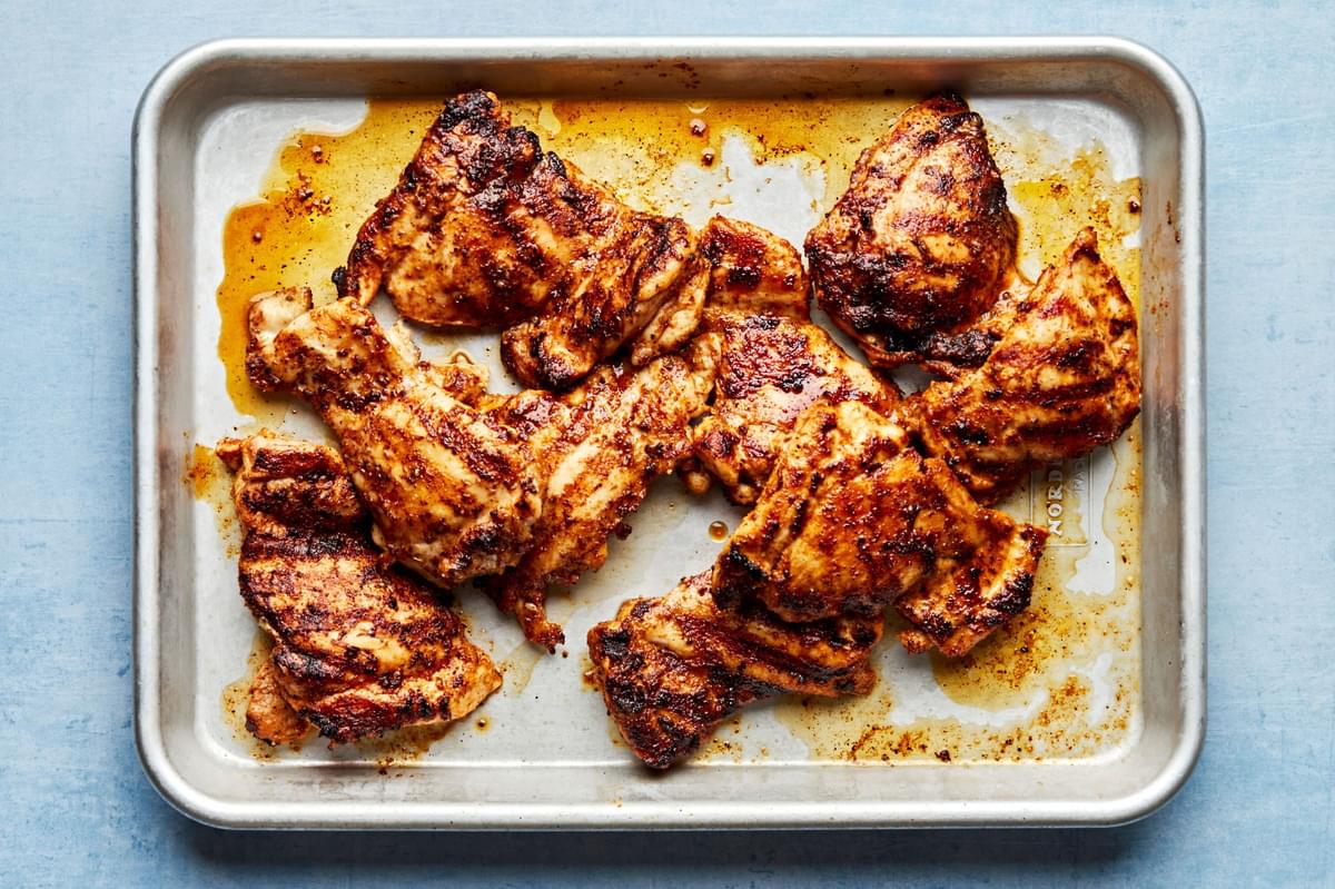 grilled chicken thighs resting on a baking sheet that were marinated in taco seasoning, olive oil and lime juice