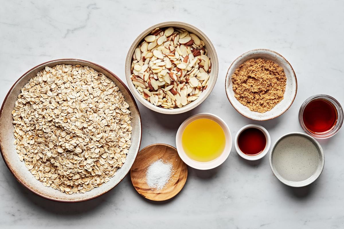 oats, sliced almonds, salt, brown sugar, maple syrup, coconut oil, olive oil and vanilla extract in bowls to make granola