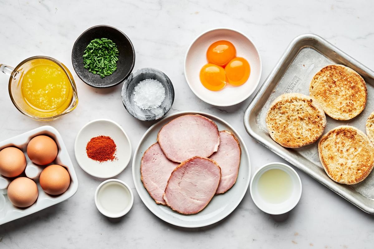 English muffins, Canadian bacon, eggs and remaining ingredients for eggs Benedict in bowls on the counter