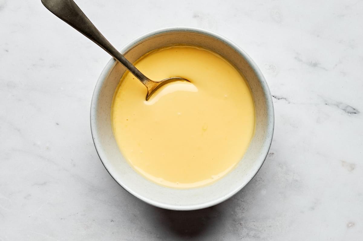 homemade hollandaise in a bowl with a spoon made with egg yolks, lemon juice and butter