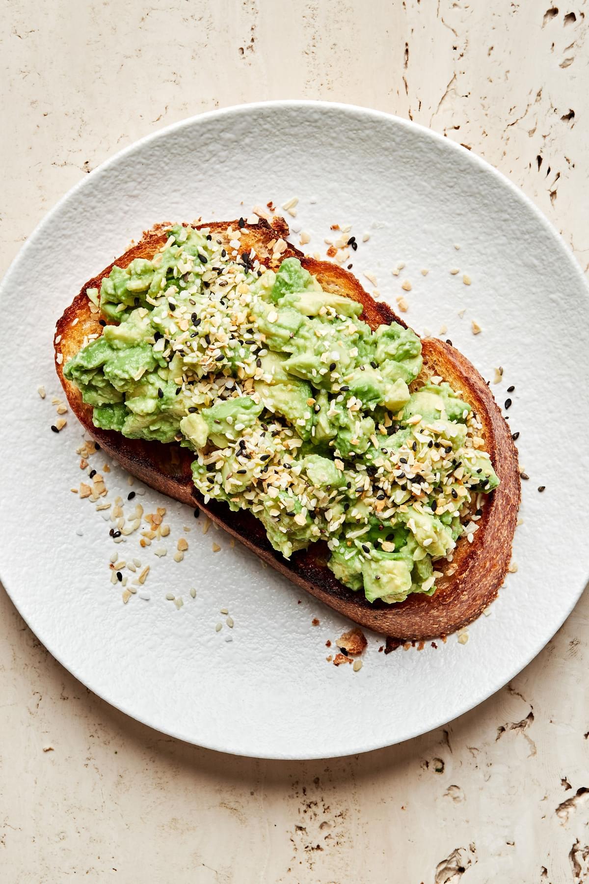 homemade everything bagel seasoning sprinkled on top of a piece of avocado toast on a plate