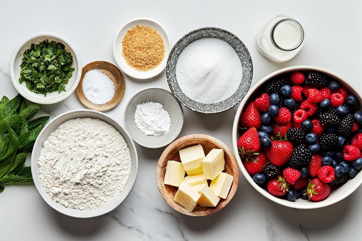 fresh berries, butter, flour, sugar, salt, mint leaves, baking powder and heavy cream in bowls to make fresh berry cobbler