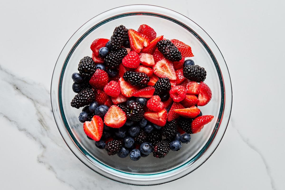 fresh blackberries, blueberries, raspberries and sliced strawberries in a glass bowl to make fresh berry cobbler