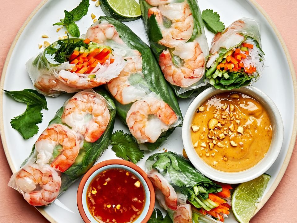 homemade fresh spring rolls on a plate with bowls of peanut sauce and sweet chili sauce for dipping