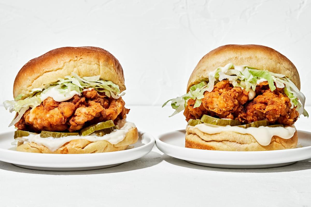 2 homemade fried chicken sandwiches on a brioche buns with garlic aioli, sliced pickles and shredded iceberg lettuce
