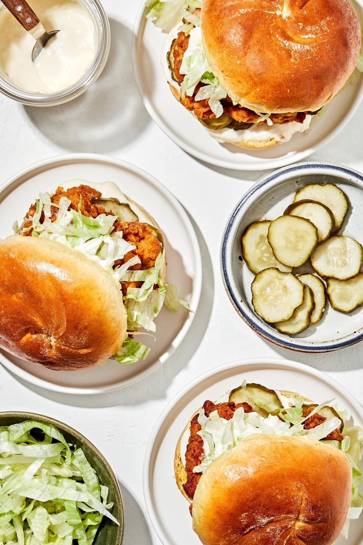 a homemade fried chicken sandwiches on a brioche buns with garlic aioli, sliced pickles and shredded iceberg lettuce