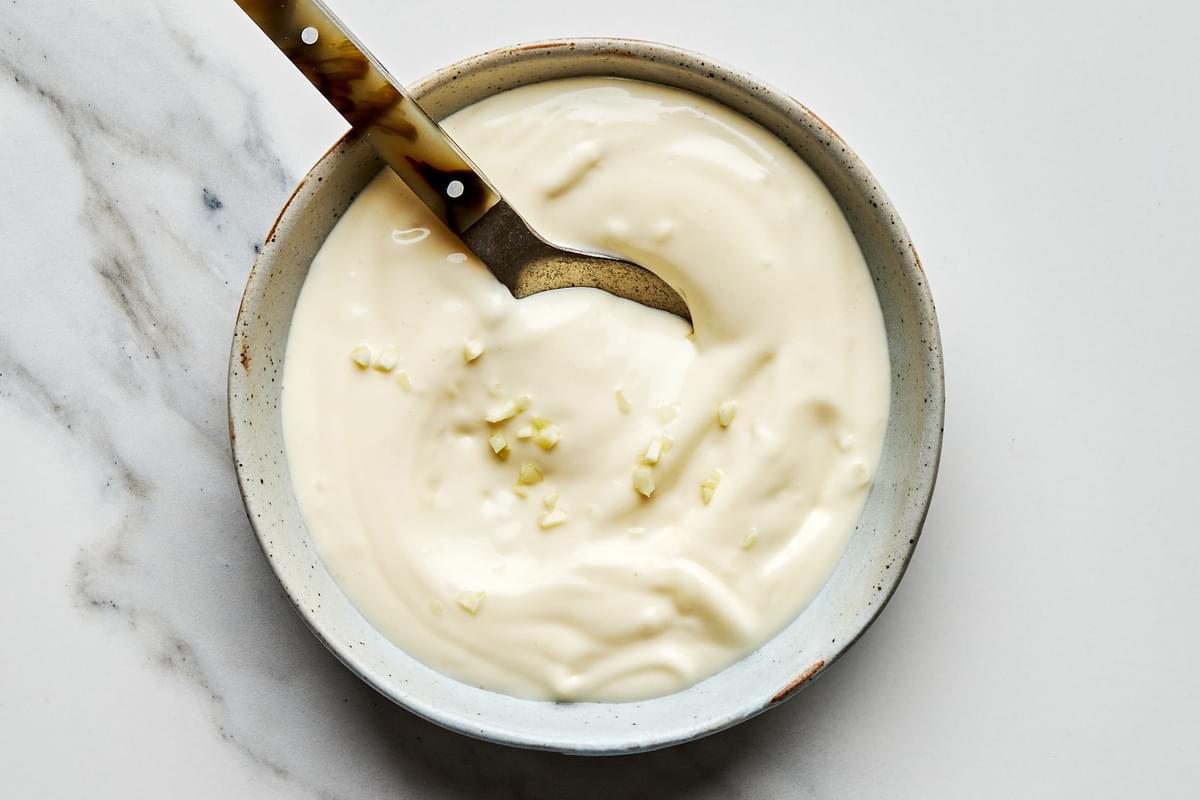 homemade garlic aioli in a bowl with a spoon made with mayo, minced garlic, lemon juice, olive oil, garlic powder & salt