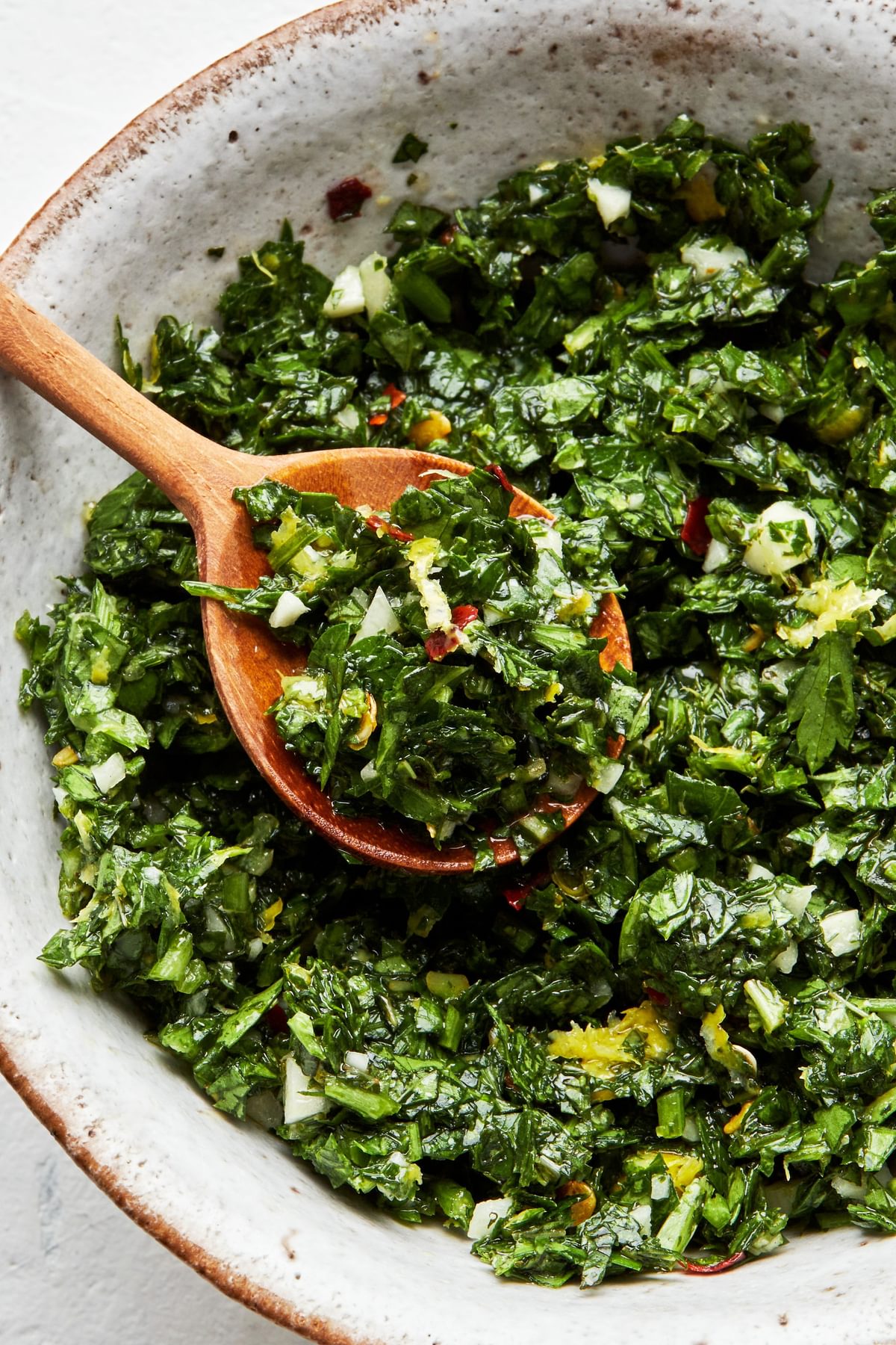 homemade gremolata in a serving bowl with a wooden spoon