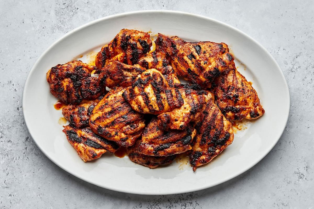 Grilled chicken thighs on a serving plate marinated in brown sugar, salt, garlic & onion powder, paprika, pepper & olive oil