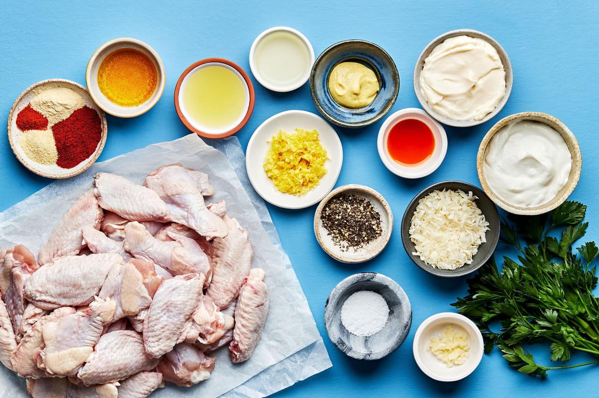 ingredients for Grilled Lemon Pepper Chicken wings in bowls on the counter including chicken wings, spices and parmesan
