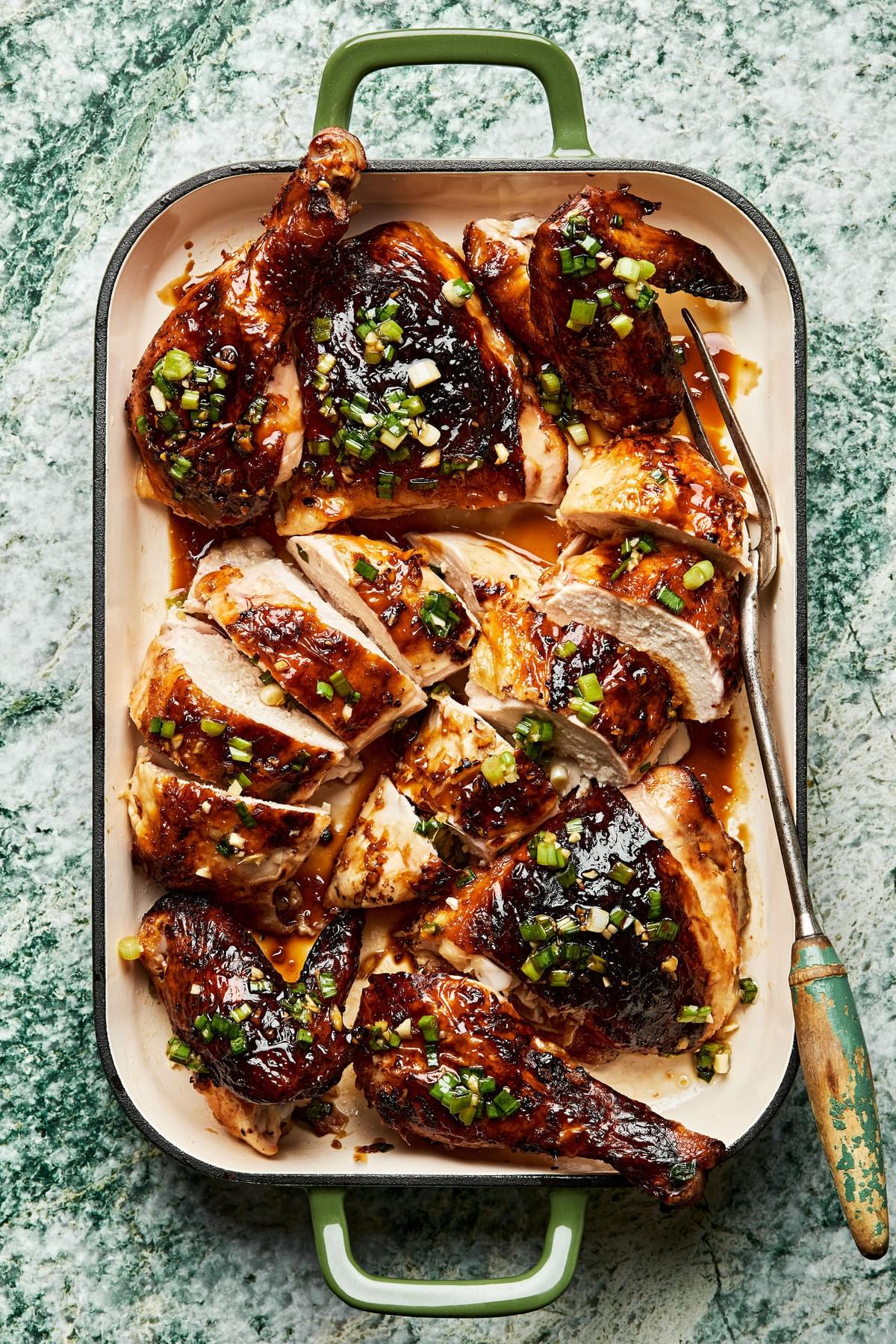 A whole grilled lemongrass chicken carved and drizzled with sriracha-brown sugar sauce and scallion oil in a serving dish