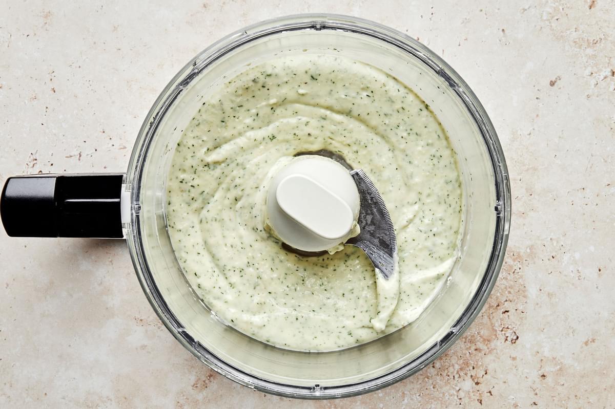 creamy dill dip in a food processor made with olive oil, mayo, garlic, dill, lemon juice, parmesan and spices