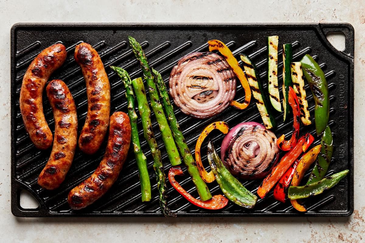 grilled sausage and mixed vegetables like asparagus, onions and peppers on a grill pan