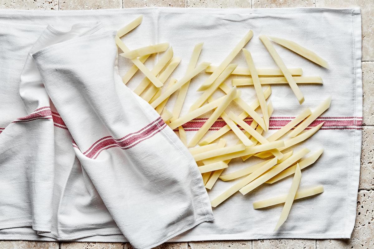 homemade raw French fries drying on a kitchen towel after being soaked in ice water to remove starch