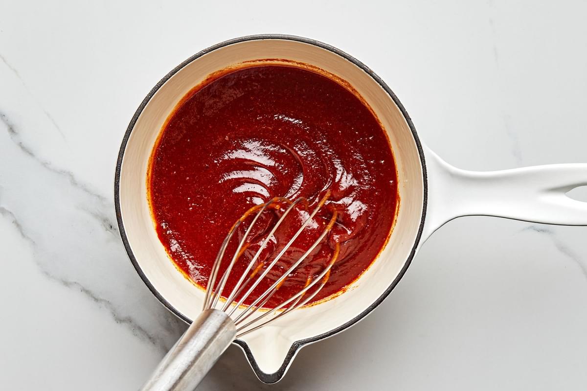 homemade bbq sauce being stirred with a whisk in a sauce pan