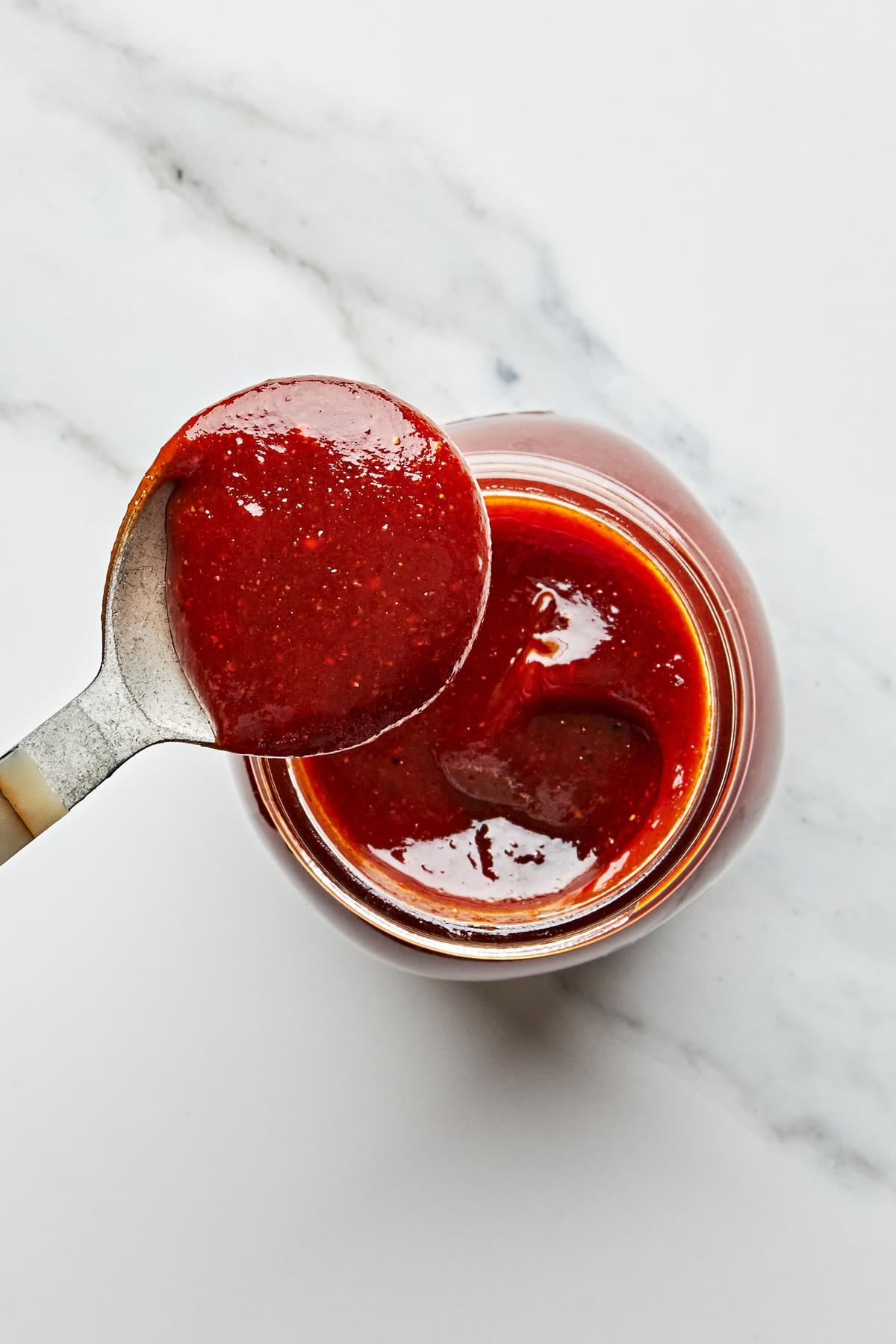 homemade bbq sauce being scooped out of a glass jar