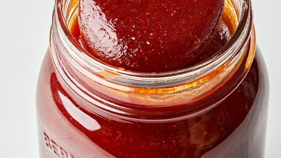 homemade bbq sauce being scooped with a spoon out of a glass jar