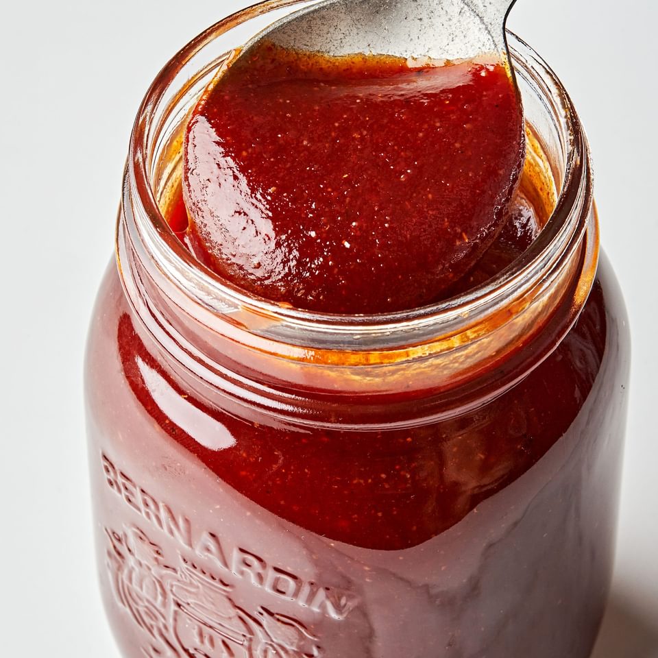 homemade bbq sauce being scooped with a spoon out of a glass jar