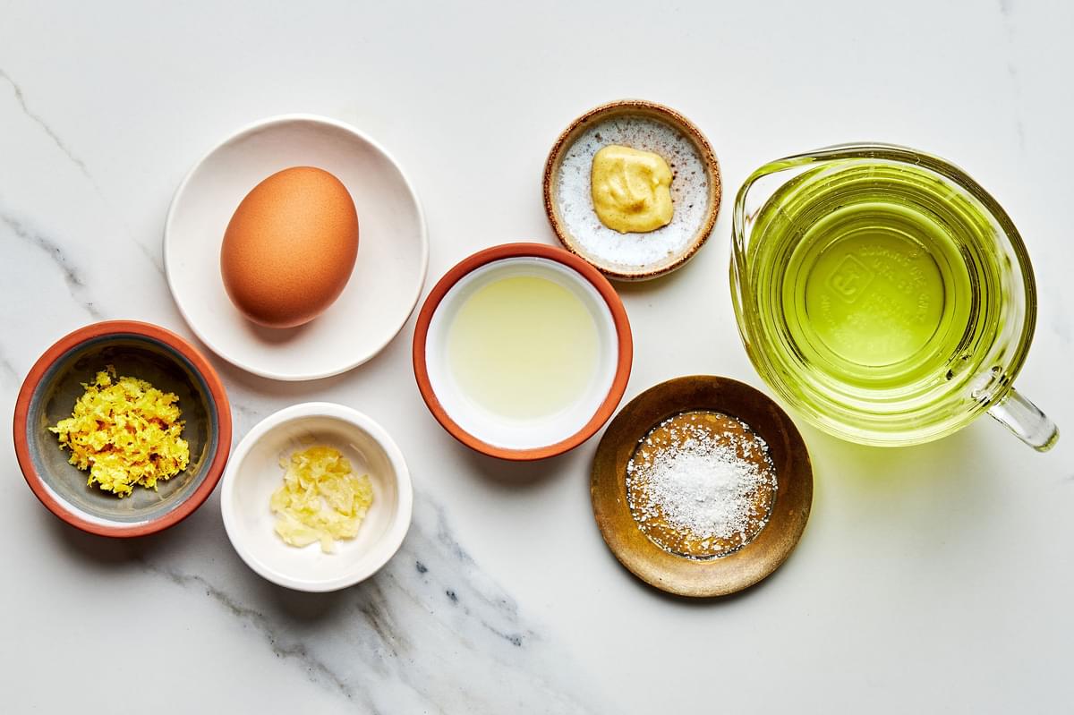 an egg, Garlic, Dijon mustard, Sea salt, Lemon juice, lemon zest and grapeseed  oil in bowls for making homemade mayonnaise