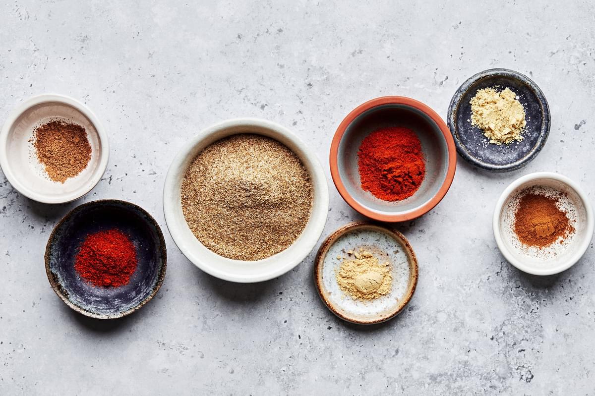 celery salt, paprika, cayenne, dry mustard, nutmeg, cinnamon, and ginger in bowls on the counter to make old bay seasoning