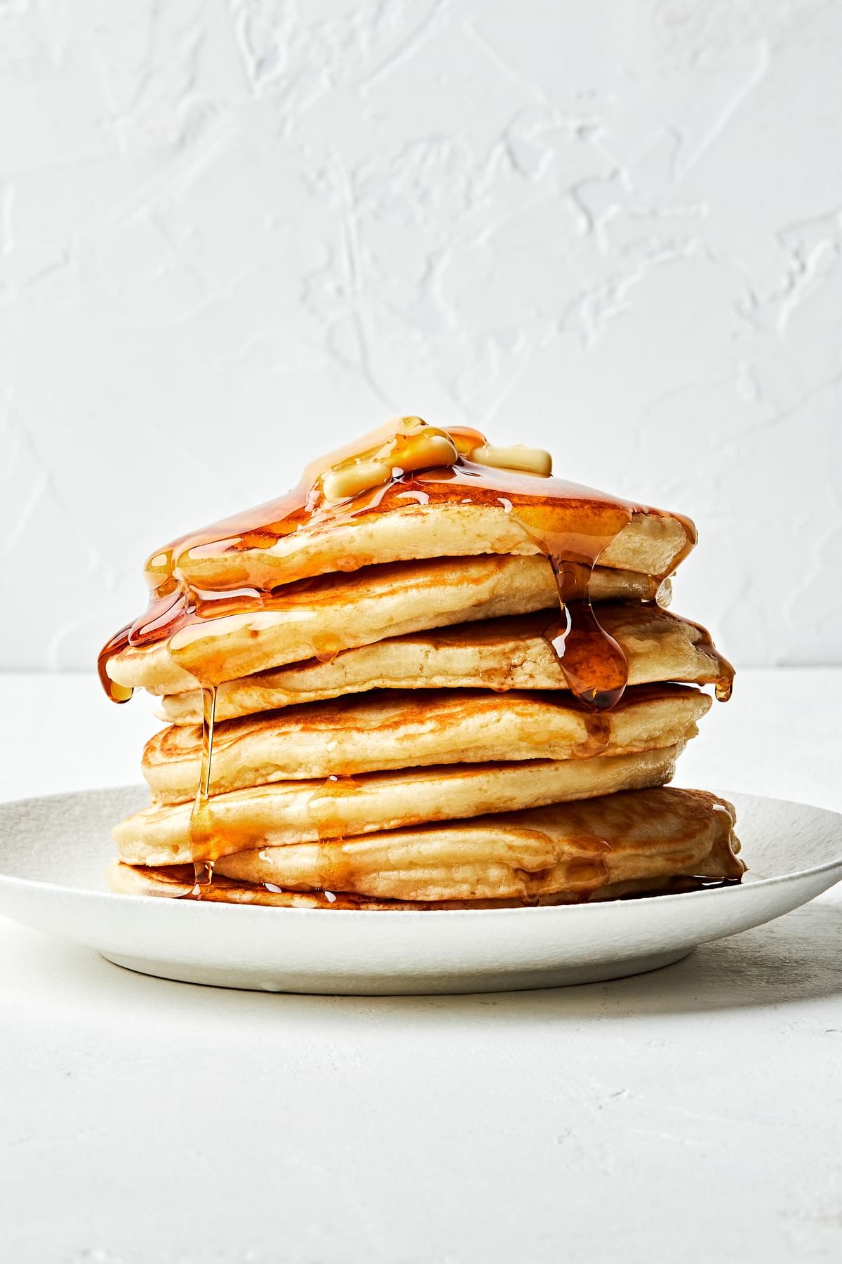 a stack of fluffy pancakes made from homemade pancake mix on plate topped with butter and drizzled with syrup