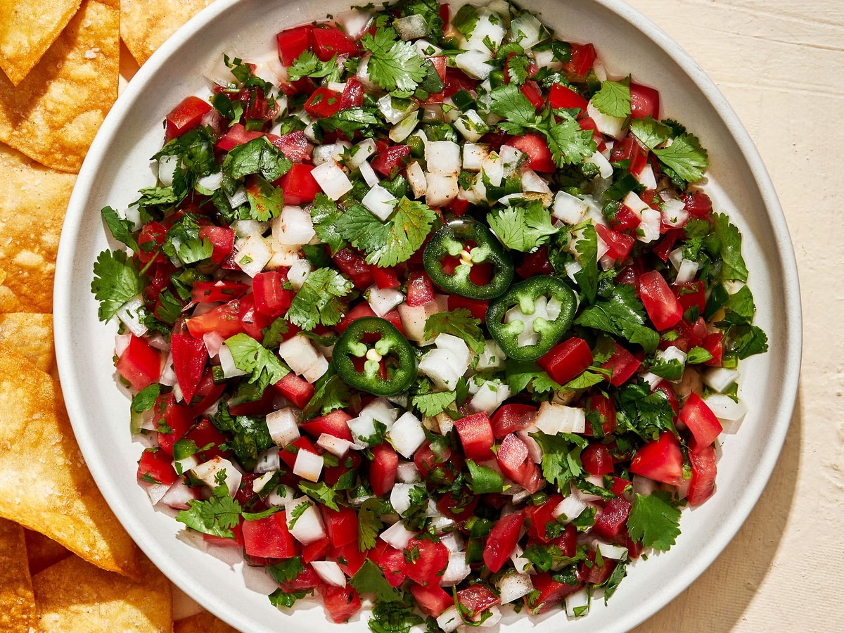 homemade pico de Gallo in a serving bowl surrounded by tortilla chips for serving