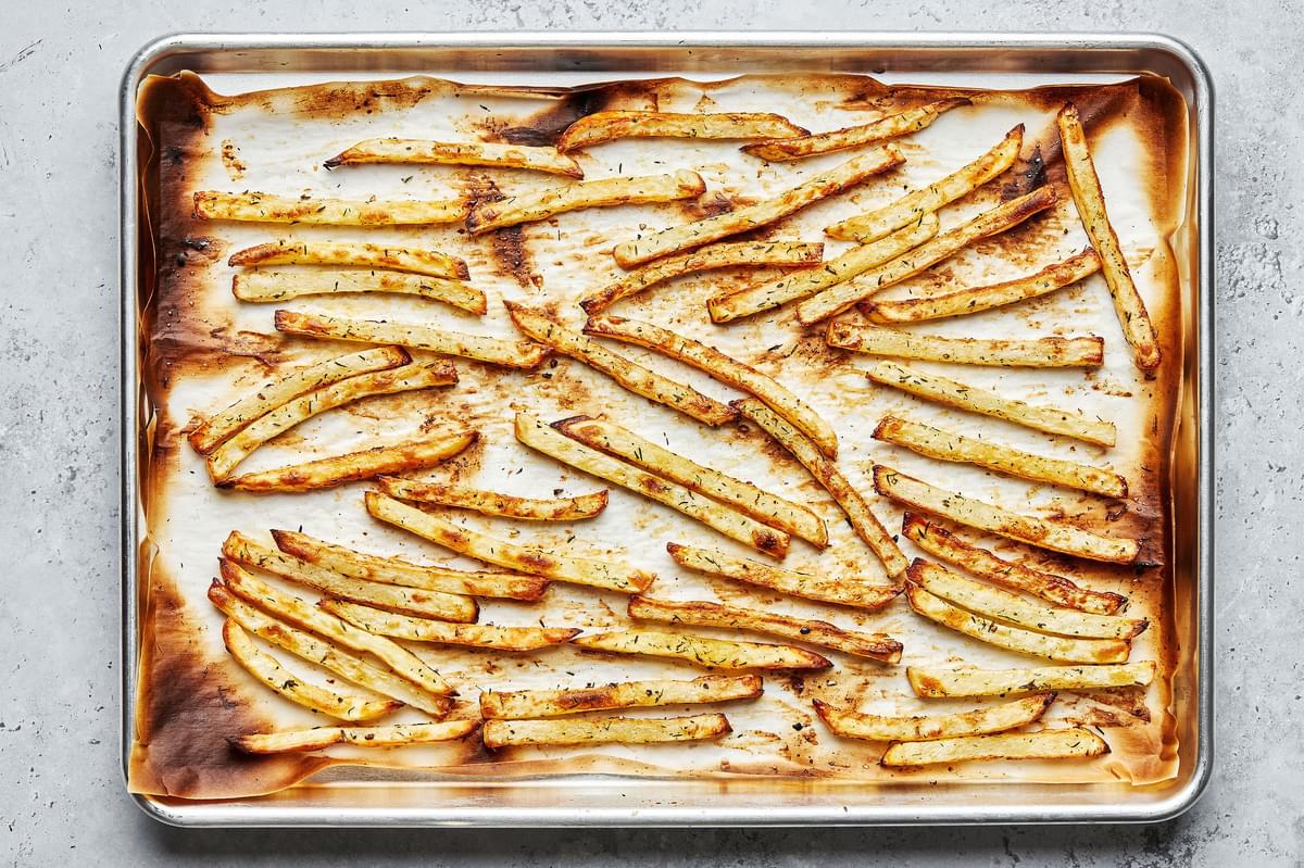 homemade oven baked fries seasoned with olive oil, salt, pepper and thyme on a parchment lined baking sheet for poutine