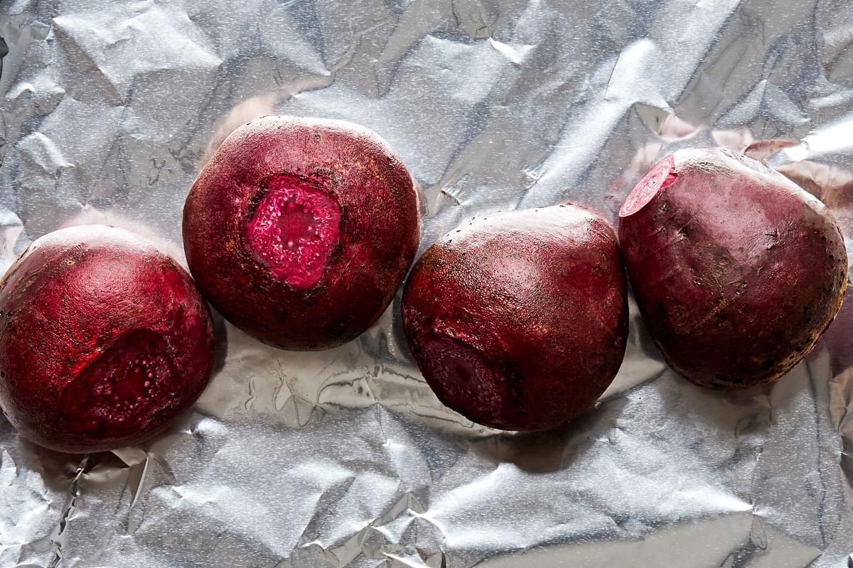 raw beets that have been washed, sitting on foil ready to be roasted in the oven