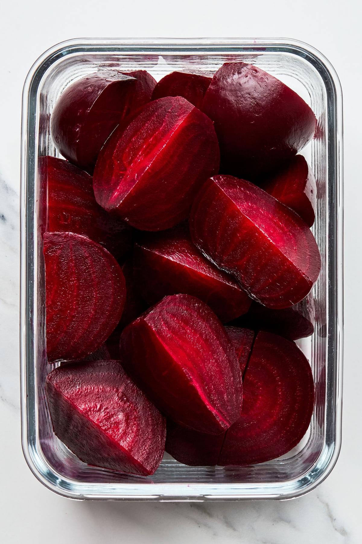 roasted beets sliced and piled in a glass Tupperware to go in the refrigerator
