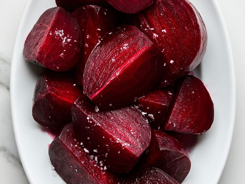 homemade roasted beets cut into quarters on a serving platter, drizzled with olive oil and sprinkled with salt and pepper