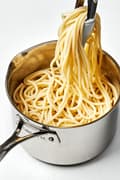 pasta noodles that have been cooked in perfectly salted water being pulled out of a pot with tongs