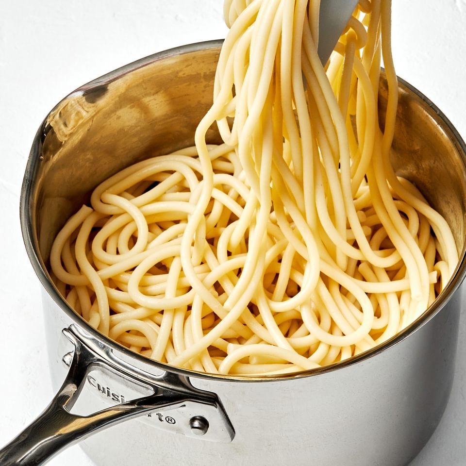 pasta noodles that have been cooked in perfectly salted water being pulled out of a pot with tongs