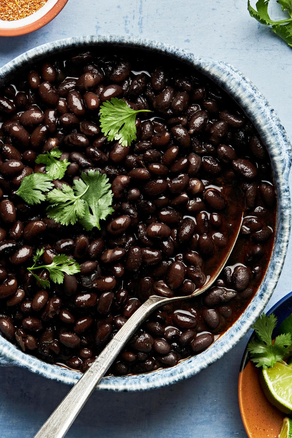homemade instant pot black beans in a bowl topped with cilantro with a serving spoon