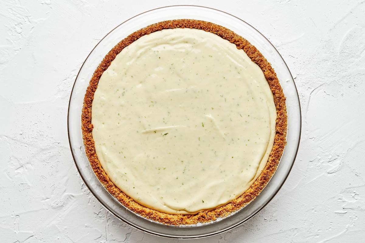 a homemade key lime pie in a glass pie pan on the counter