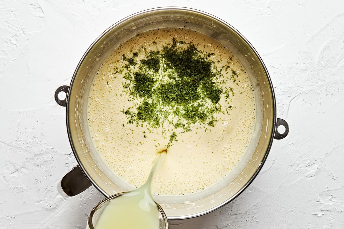 lime juice being poured into a stand mixer containing sweetened condensed milk, egg yolks and key lime zest