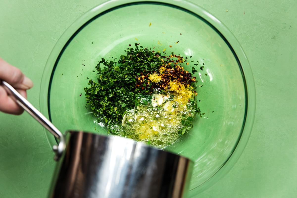 warmed butter and olive oil being poured in a bowl with garlic, parsley, lemon zest, red pepper flakes and sea salt