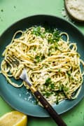 homemade linguine with lemon garlic sauce topped with grated parmesan and chopped parsley on a plate with a fork