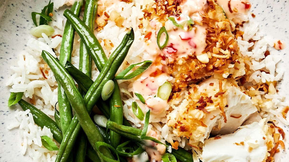 A macadamia nut crusted fish bowl with coconut rice, green beans and a sweet chili mayo sauce drizzled on top