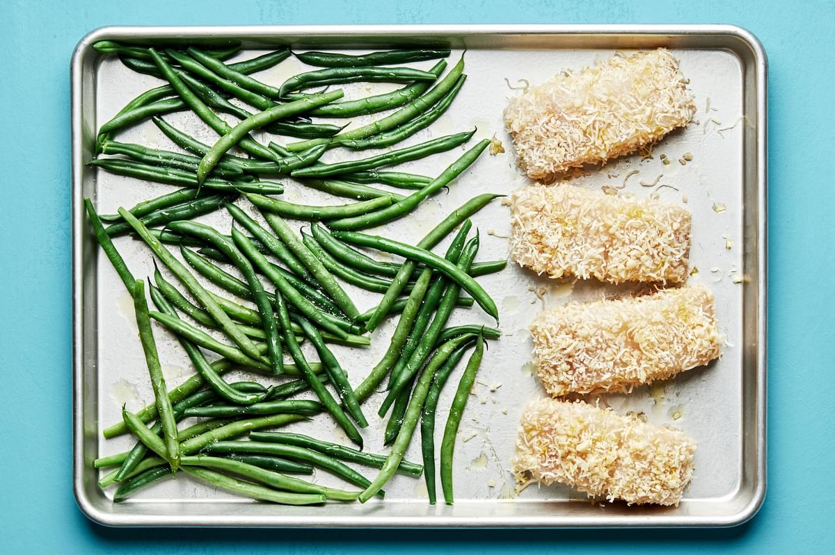 green beans and macadamia nut crusted fish on a baking sheet ready to be baked in the oven