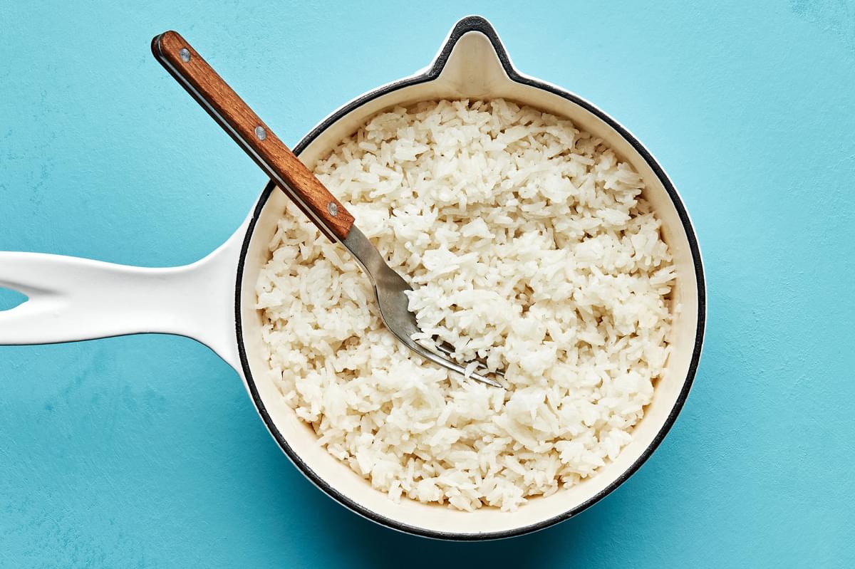 coconut milk-and-ginger-scented rice in a pot with a spoon for macadamia nut crusted fish bowls