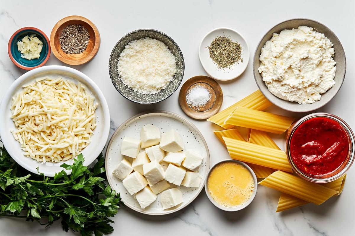 ricotta, mozzarella, parmesan, eggs, parsley, garlic, salt, pepper, Italian seasoning, marinara, and manicotti in bowls