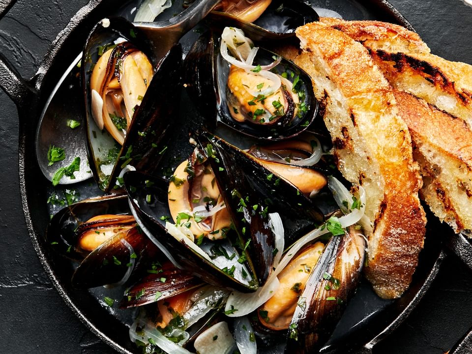 a pot of mussels in wine sauce served with crusty bread