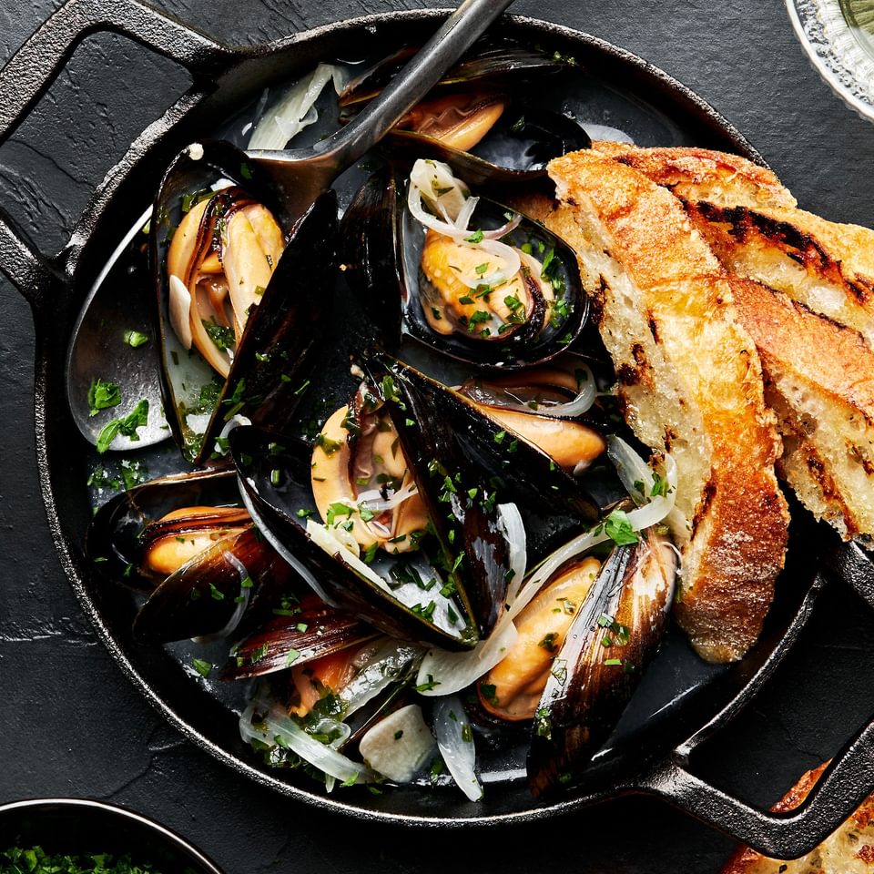 a pot of mussels in wine sauce served with crusty bread